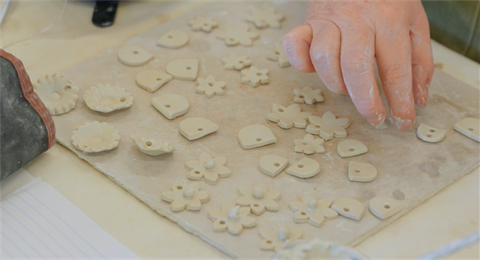 Hands shaping clay into small shapes